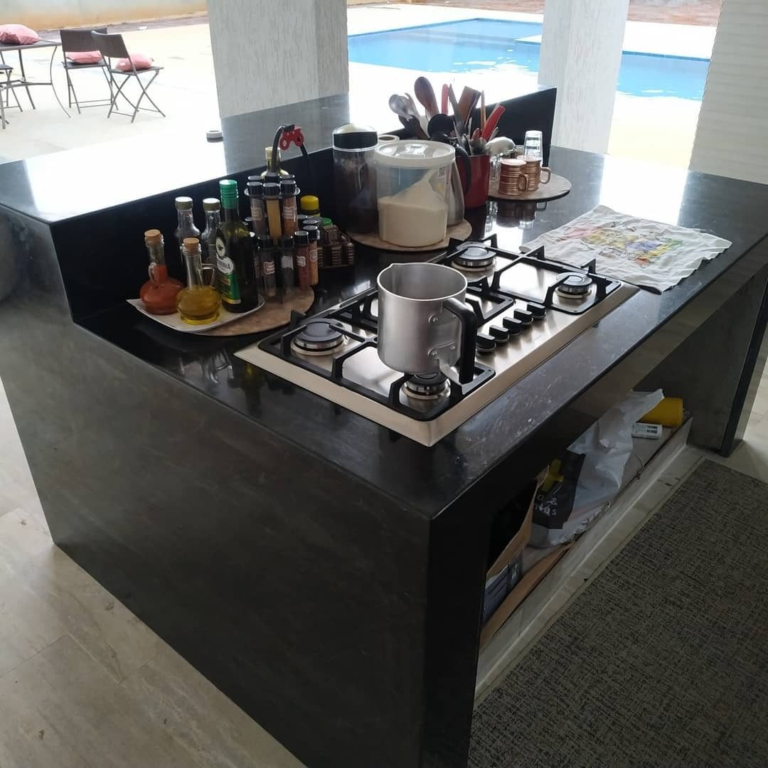 Ilha gourmet com cooktop em bancada de pedra escura