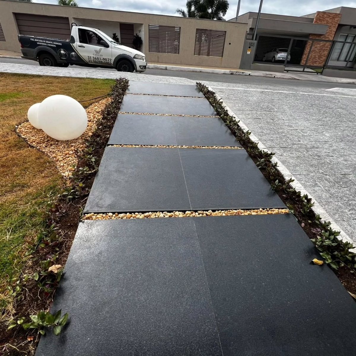 Piso externo em pedra escura com faixas de seixo